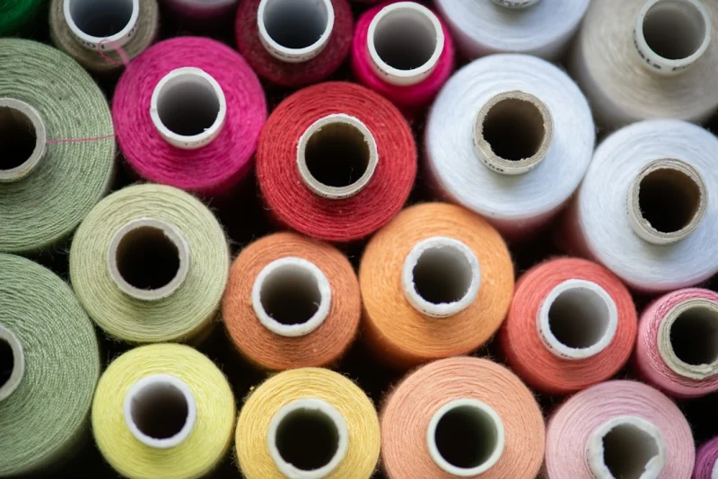 Cones of dyed yarn lined up in a range of colors.