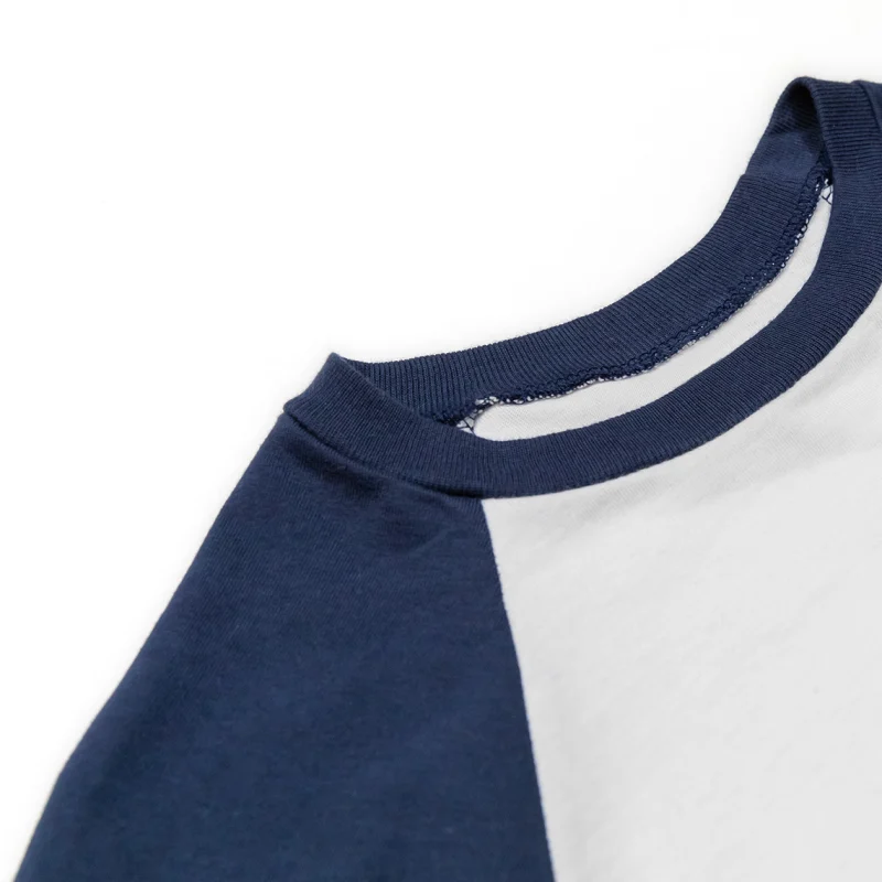 Close view of a rib neckband sewn into the neckline of a navy and white raglan tee.