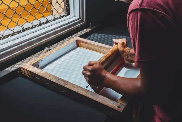 A printer pulling ink across a screen with a squeegee.