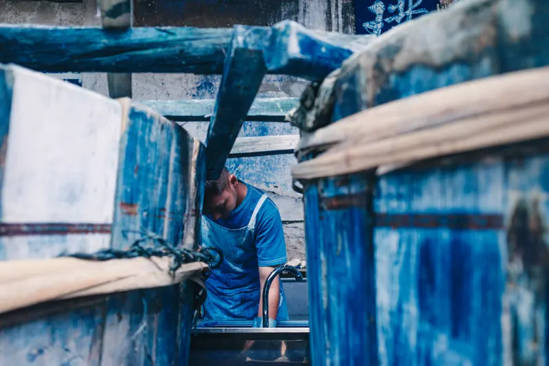 A worker among blue-stained dye vats in a fabric dyeing workshop.