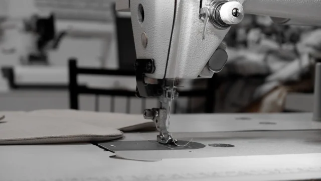An industrial sewing machine stitching a fabric panel.