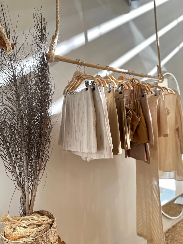 Beige and cream skirts clipped to wooden hangers on a rail.