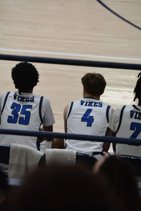 Players on a bench seen from behind in white jerseys with blue lettering and the numbers 35 and 4.