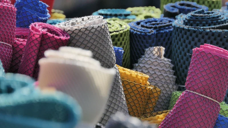 Rolls of colored mesh fabric stacked at a fabric market.