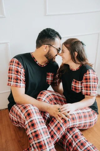 A couple in matching plaid pajama pants and black tees with plaid pockets.