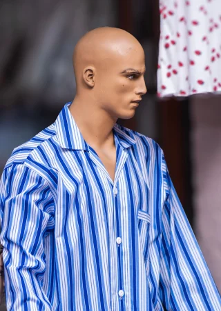 A blue and white striped pajama shirt with a notched collar on a mannequin.