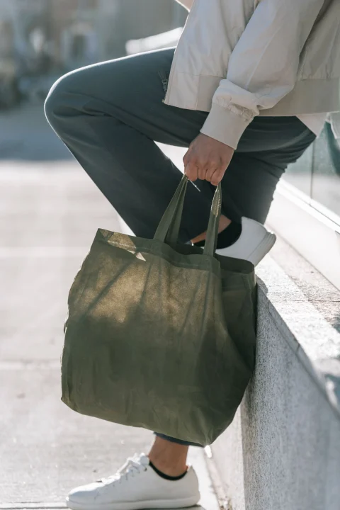 An olive canvas tote carried by its handles.