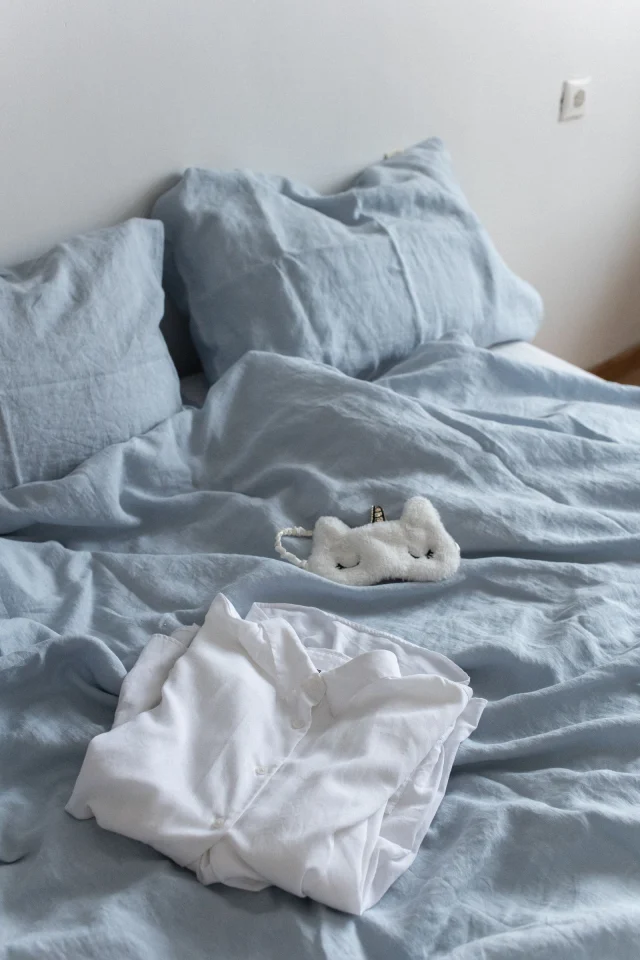 A folded white sleep shirt on light blue bedding.