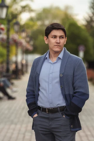 Man wearing a navy shawl-collar cardigan buttoned over a light blue shirt.
